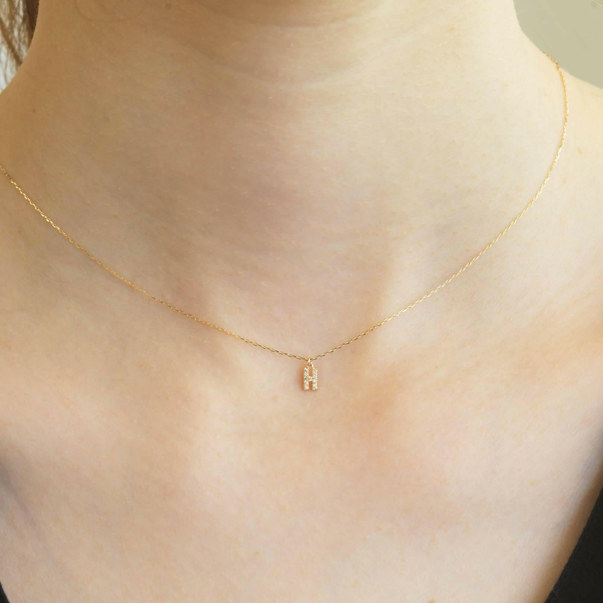 胸元で輝く10KゴールドHイニシャルネックレス(ダイヤ付きチャーム)を着用した女性モデルのアップ