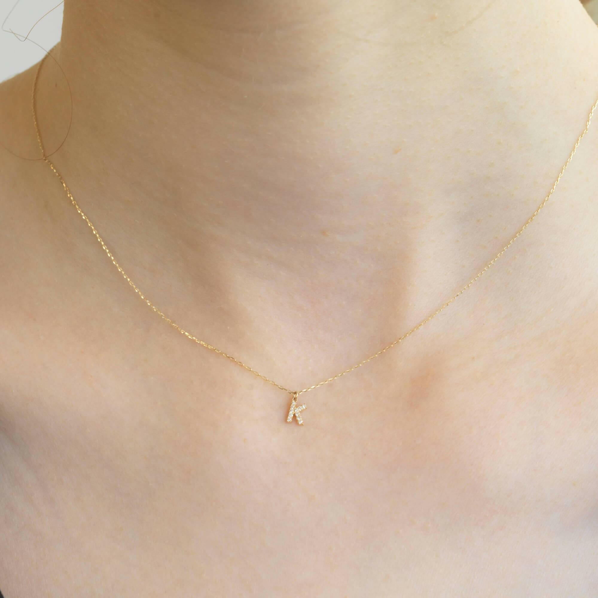 胸元で輝く10KゴールドKイニシャルネックレス(ダイヤ付きチャーム)を着用した女性モデルのアップ