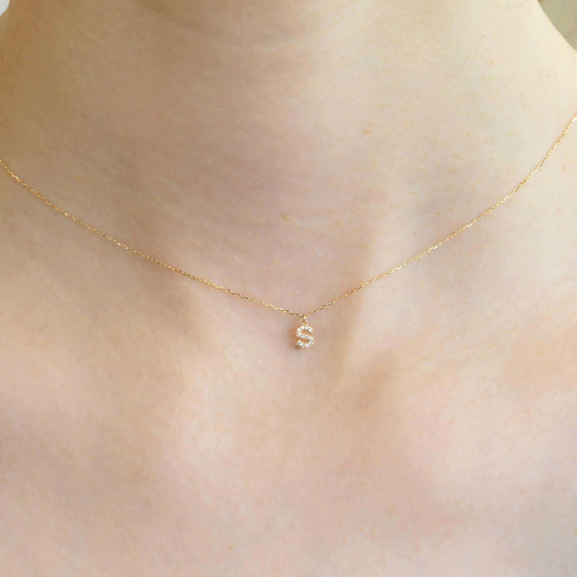 胸元で輝く10KゴールドSイニシャルネックレス(ダイヤ付きチャーム)を着用した女性モデルのアップ