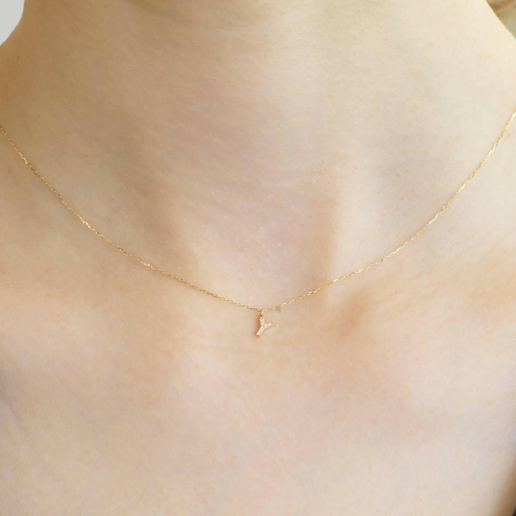 胸元で輝く10KゴールドYイニシャルネックレス(ダイヤ付きチャーム)を着用した女性モデルのアップ
