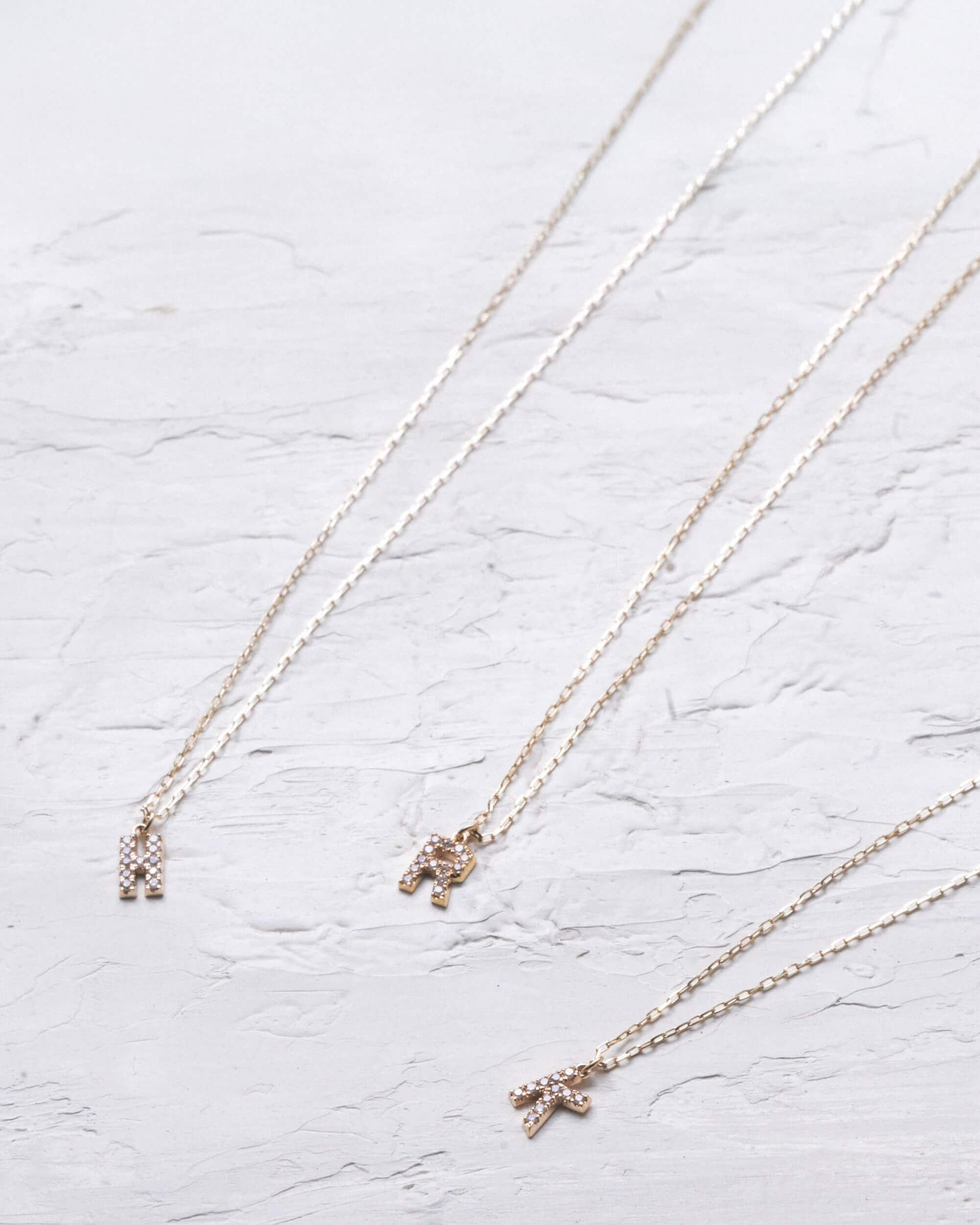 10Kゴールド イニシャルネックレス 置き画 | 天然ダイヤモンドが輝く華奢なチェーンとアルファベットチャーム