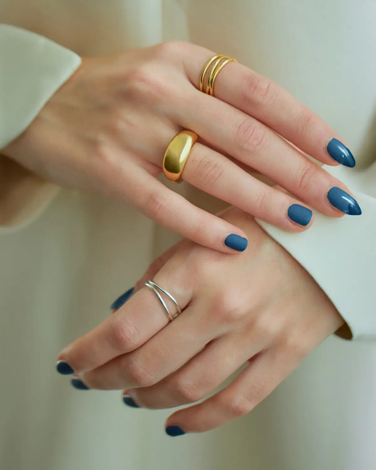 左手にシルバーの3連ウェーブリング、右手にゴールドリングを着けたミックスカラーの手元スタイリング。