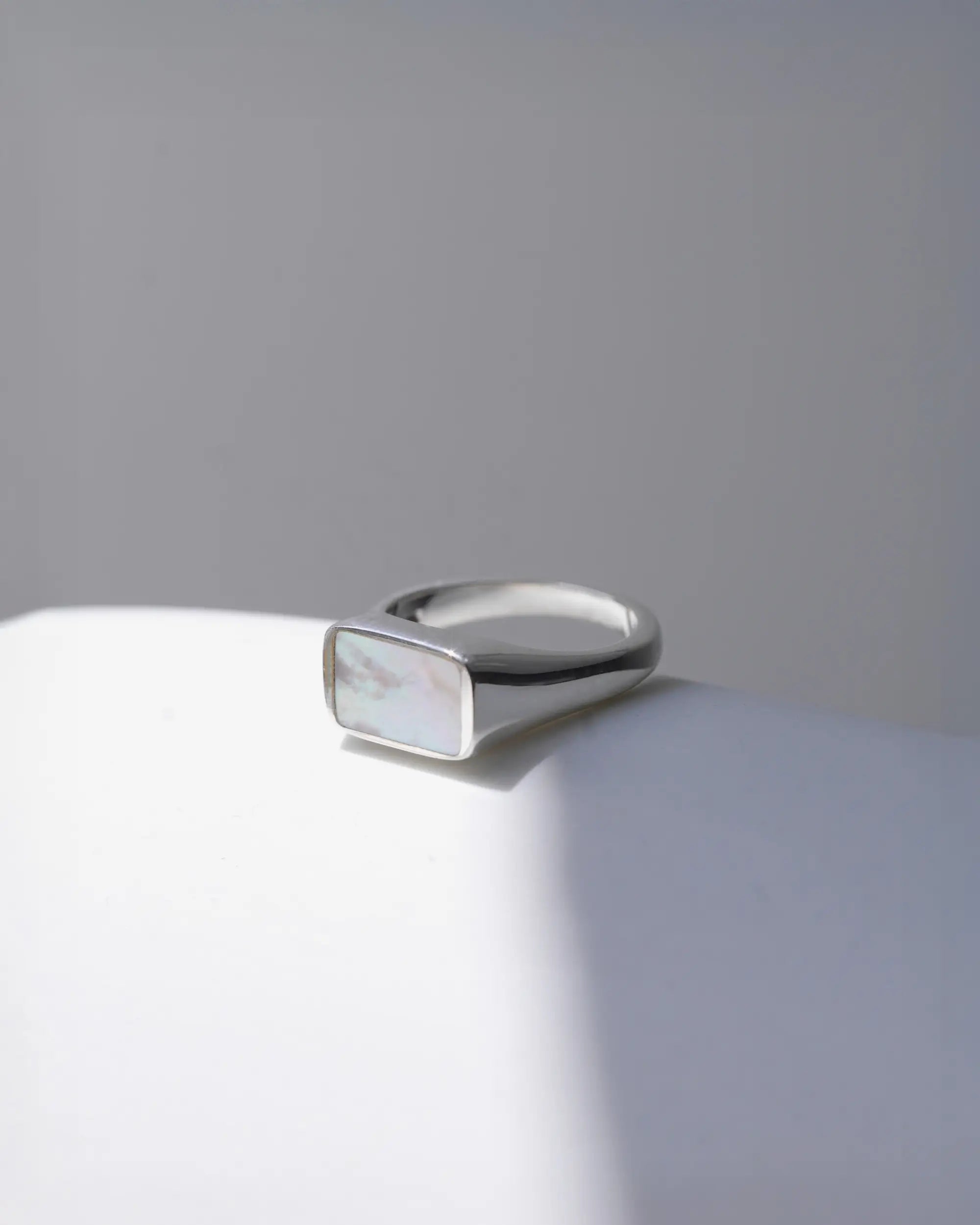 トップに埋め込まれたマザーオブパールに自然光が当たっている、シルバー925 ミスティング シルバーの地金とマザーオブパールの表面はフラットに仕上げれられている