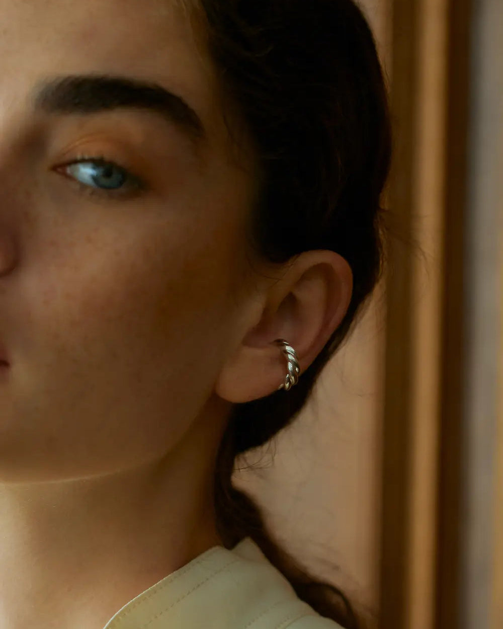 シルバーのウェーブイヤーカフを着用した横顔アップ。ピアスホールがない方でもスタイリングを楽しめるイヤーカフ。
