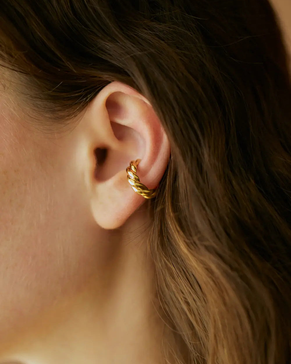 ウェーブイヤーカフ(ゴールド)の耳元ドアップ。開口部約3mmで着脱しやすく、重ね付けにも最適な17mm×17mmのミニマルサイズ。