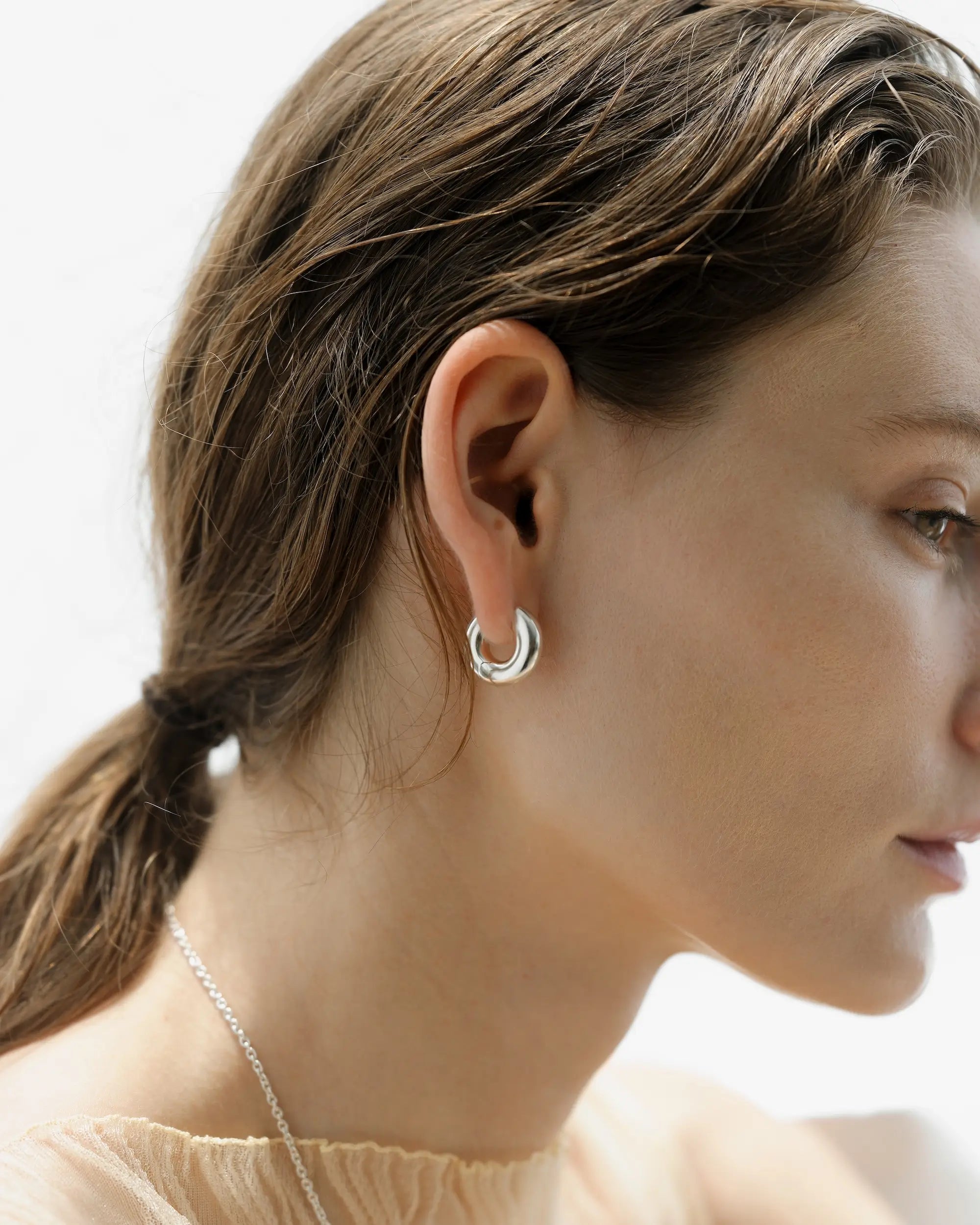 フラグメントフープピアス シルバー 横顔 | 厚みのある有機的なフォルムが耳元に陰影を作る
