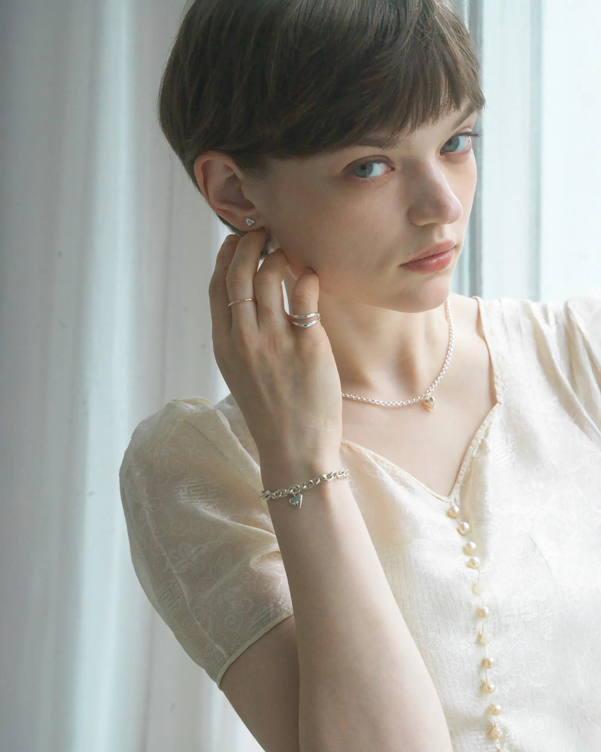 シンプルなオープンハートのネックレスを身につけたモデル。オフィスからデートまで幅広く使える、タイムレスで品のあるデザイン。