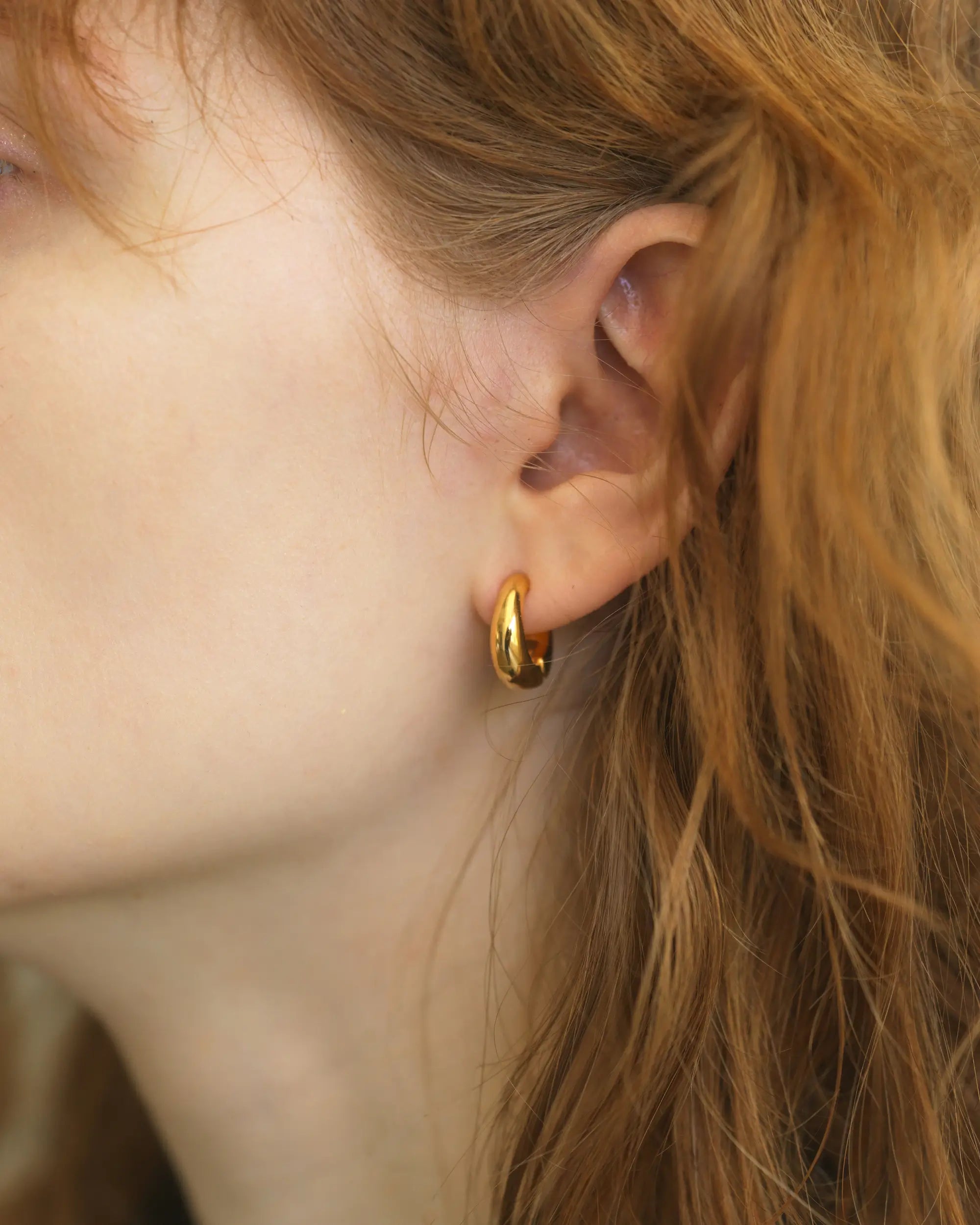 イヤーカフとしても使える2way仕様の痛くないゴールドイヤリング(Mサイズ)を着用した、立体的なフォルムが際立つ耳元の拡大写真。