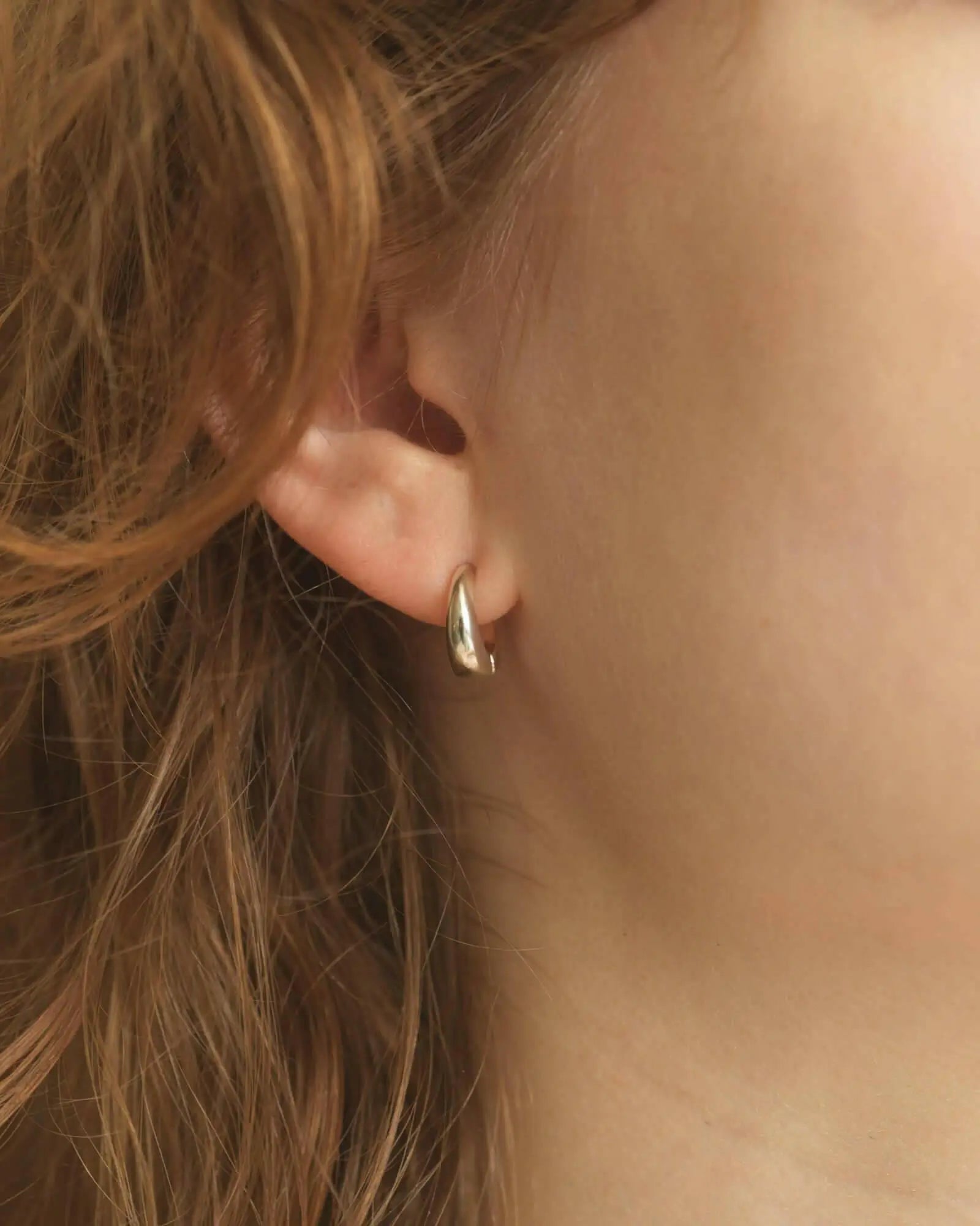 金具が目立たないシルバー925製のヒンジドフープイヤリングを耳たぶに着用した、耳元のクローズアップ画像。