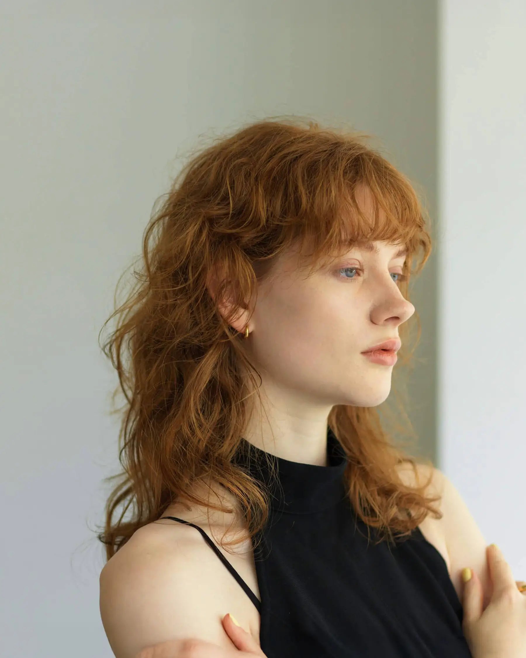 黒いノースリーブトップスを着た女性が、小ぶりなゴールドのノンホールイヤリングを着用している洗練された横顔。