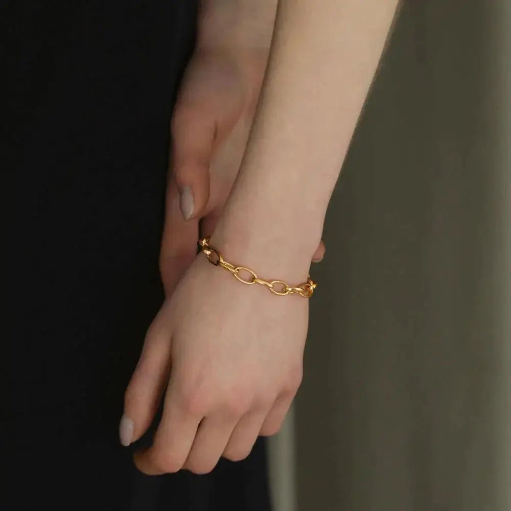 オーバルチェーンブレスレット ゴールド 手元 | シンプルな黒トップスを引き立てる大人のボリュームブレス