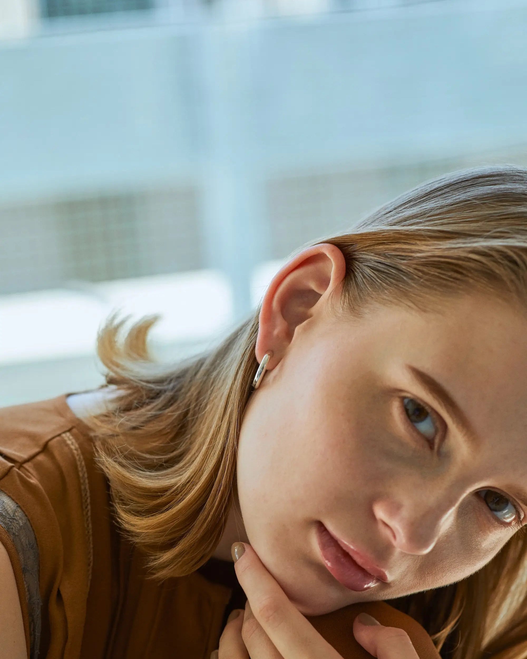 オーバルフープピアス M(シルバー)の着用画像。約3.5mmの程よい厚みが、カジュアルな装いをモードな雰囲気に格上げするジュエリー。