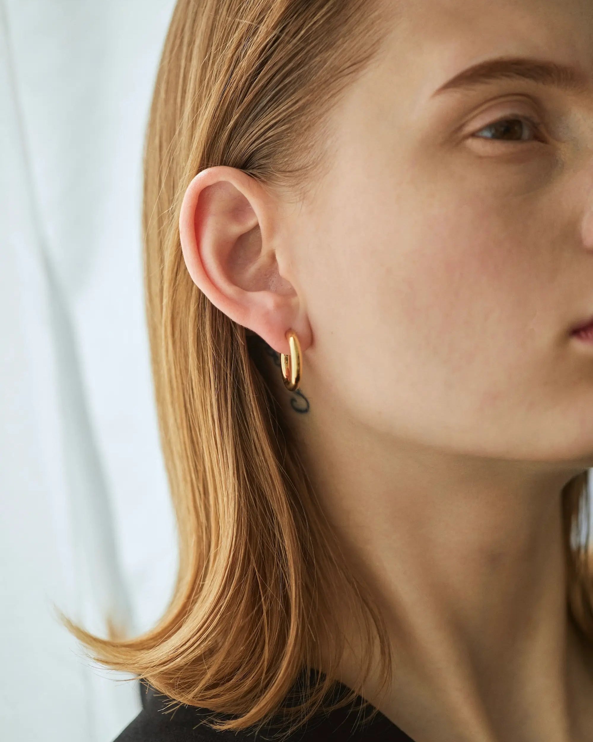 18Kゴールドコーティングを施したオーバルフープピアス M(ゴールド)の着用横顔。金属アレルギーに配慮した高品質なSilver925素材。