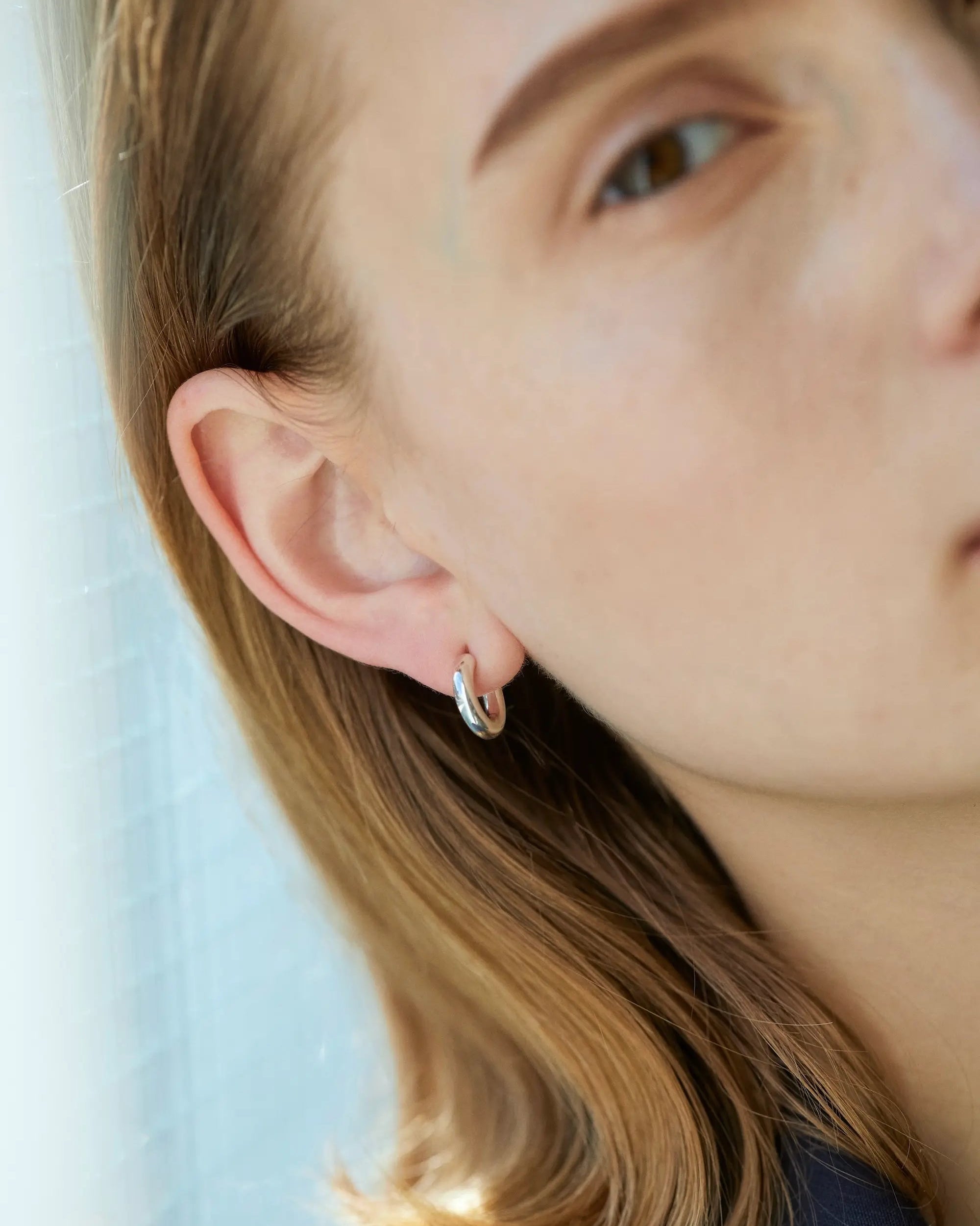 オーバルフープピアス S(シルバー)の耳元ドアップ画像。縦のラインを強調する約14mmの楕円フォルムが、横顔をすっきりとスマートに見せる洗練されたピアス。