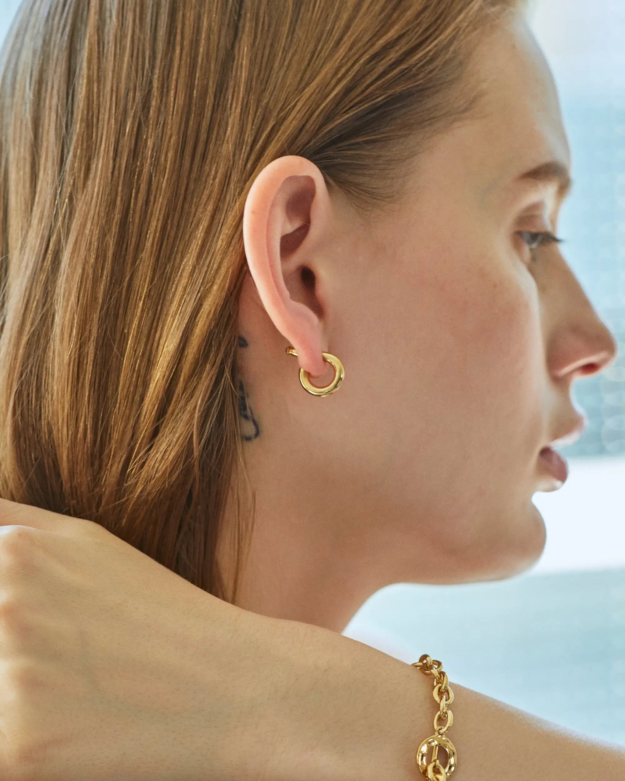ゴールドのオーバルフープピアス S着用画像。主張しすぎない約14mmのミニマルなサイズ感で、日常のあらゆるシーンにシームレスに溶け込みます。