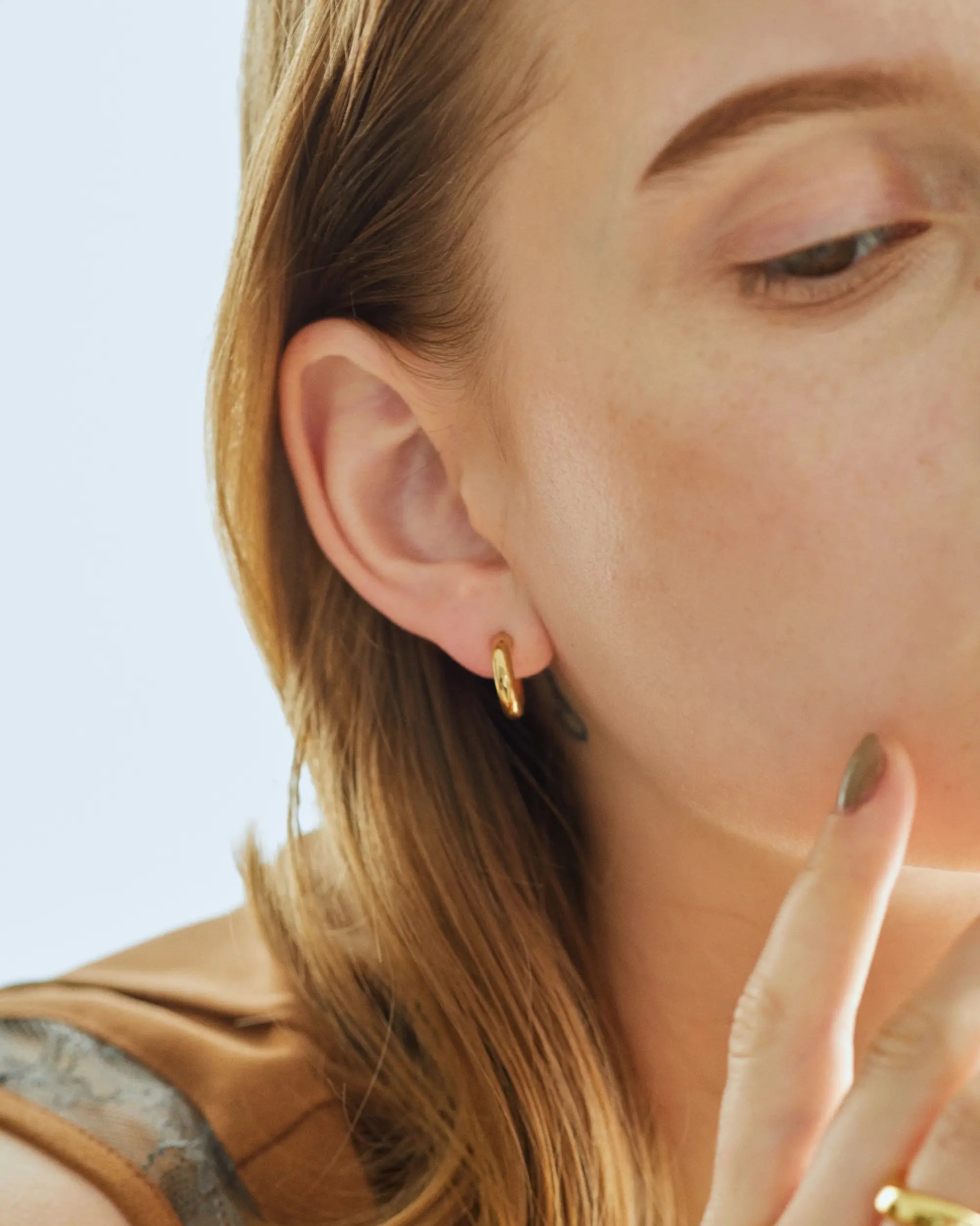 ゴールドのオーバルフープピアス S着用モデル。ジェンダーレスで使えるクリーンなデザインで、男女問わずペアピアスとしても人気のジュエリー。