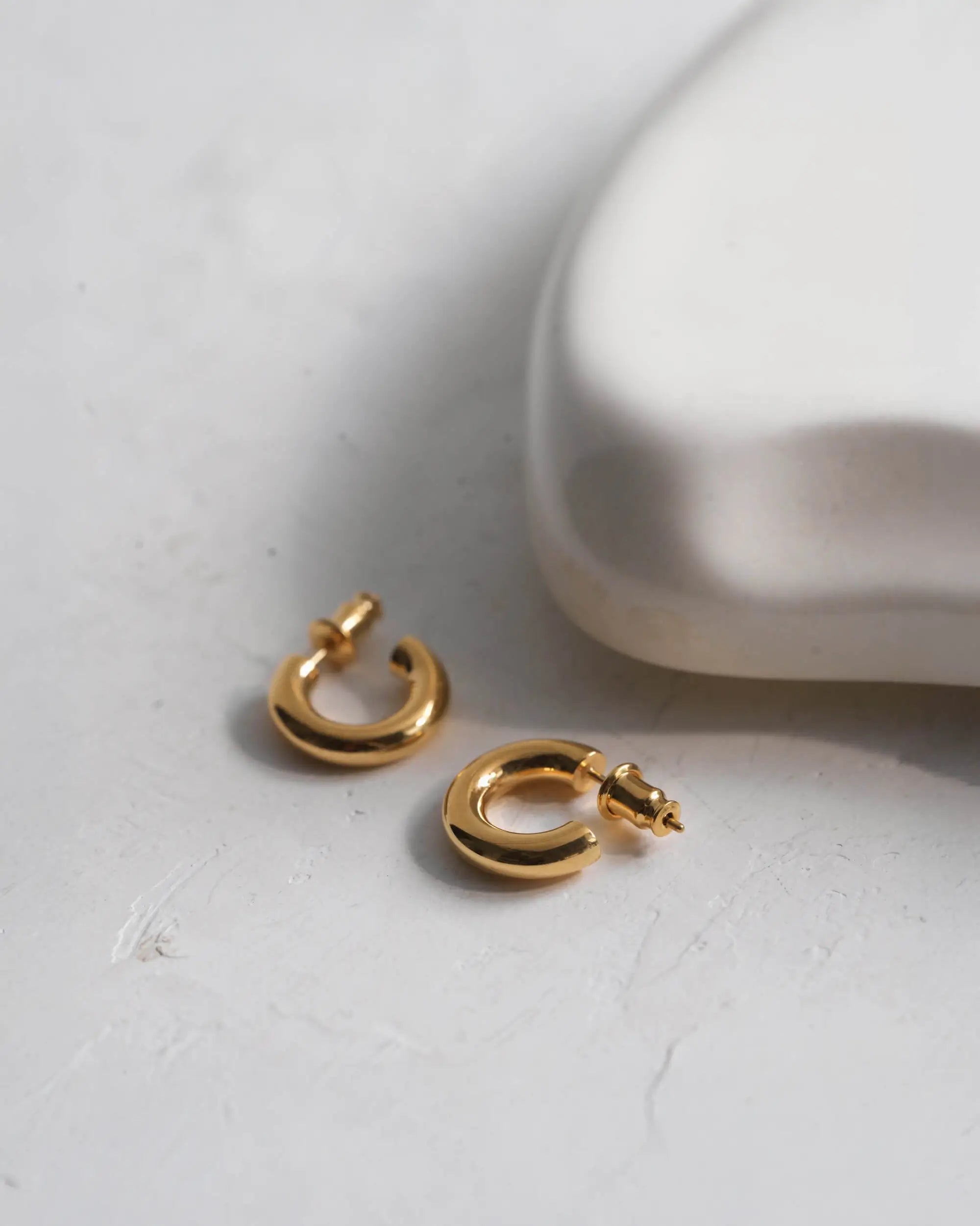 オーバルフープピアス S(ゴールド)の美しい置き画。厚みのある18Kコーティングで色褪せない輝きを保つ、高品質なスターリングシルバー製ピアス。