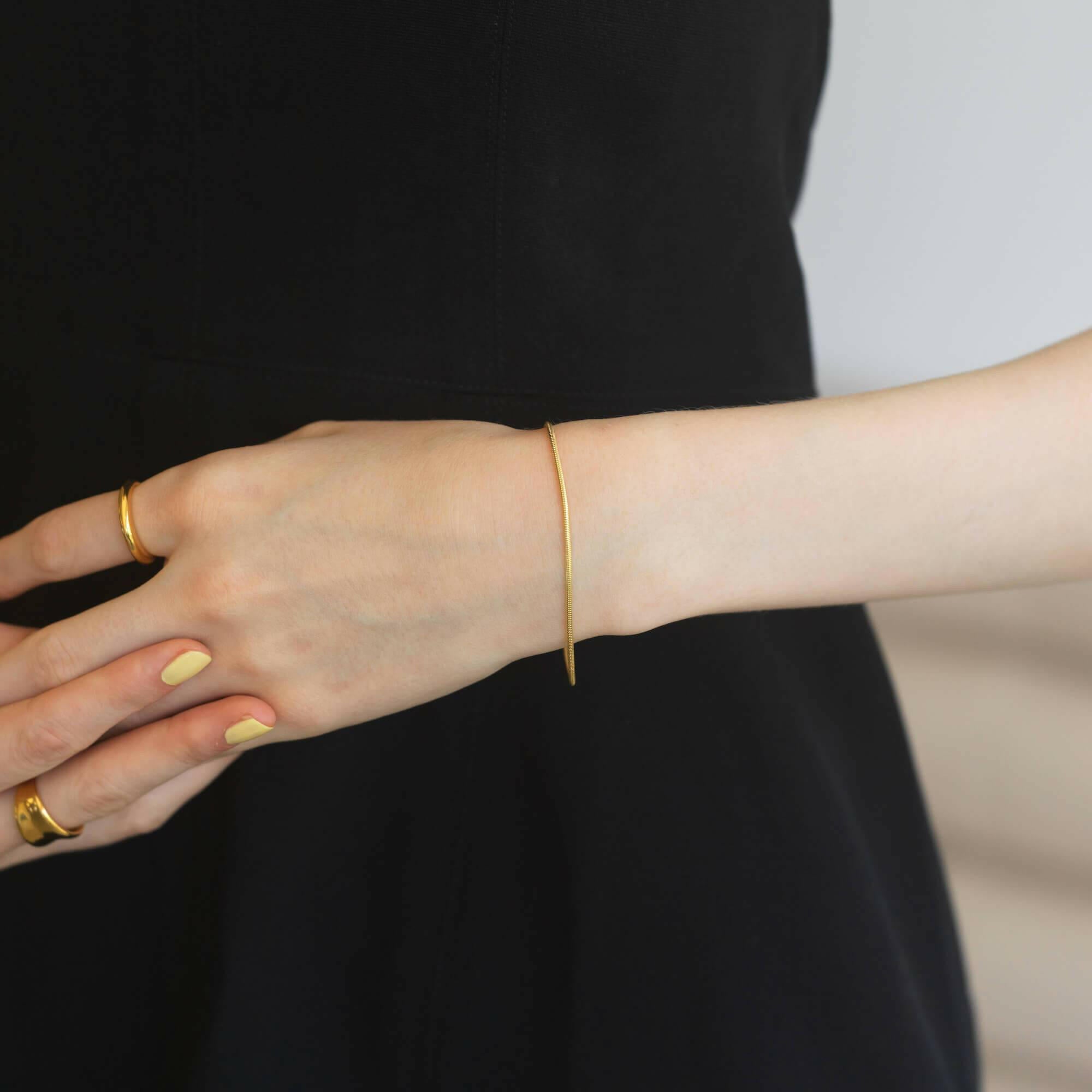 ラウンドスネークブレスレット ゴールド 手元 | 重ね付けのベースとしても優秀な細身のスネークチェーン