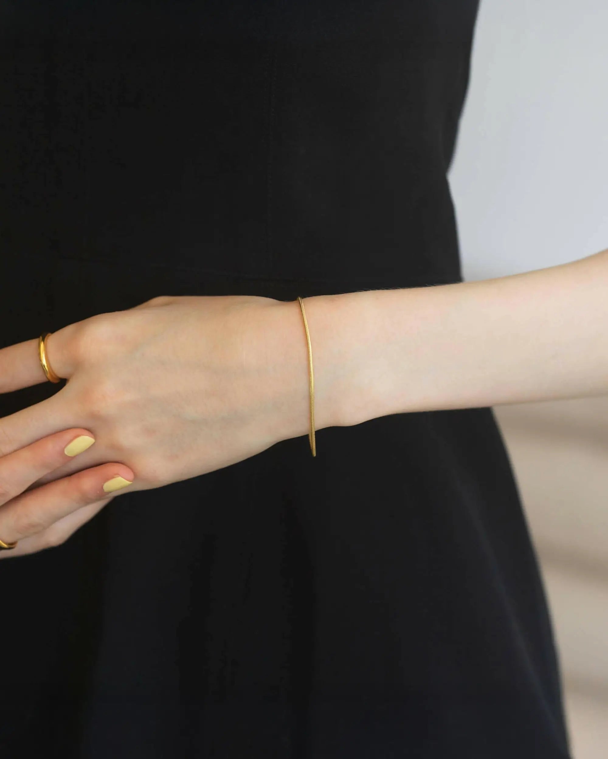 ラウンドスネークブレスレット ゴールド 手元 | 重ね付けのベースとしても優秀な細身のスネークチェーン