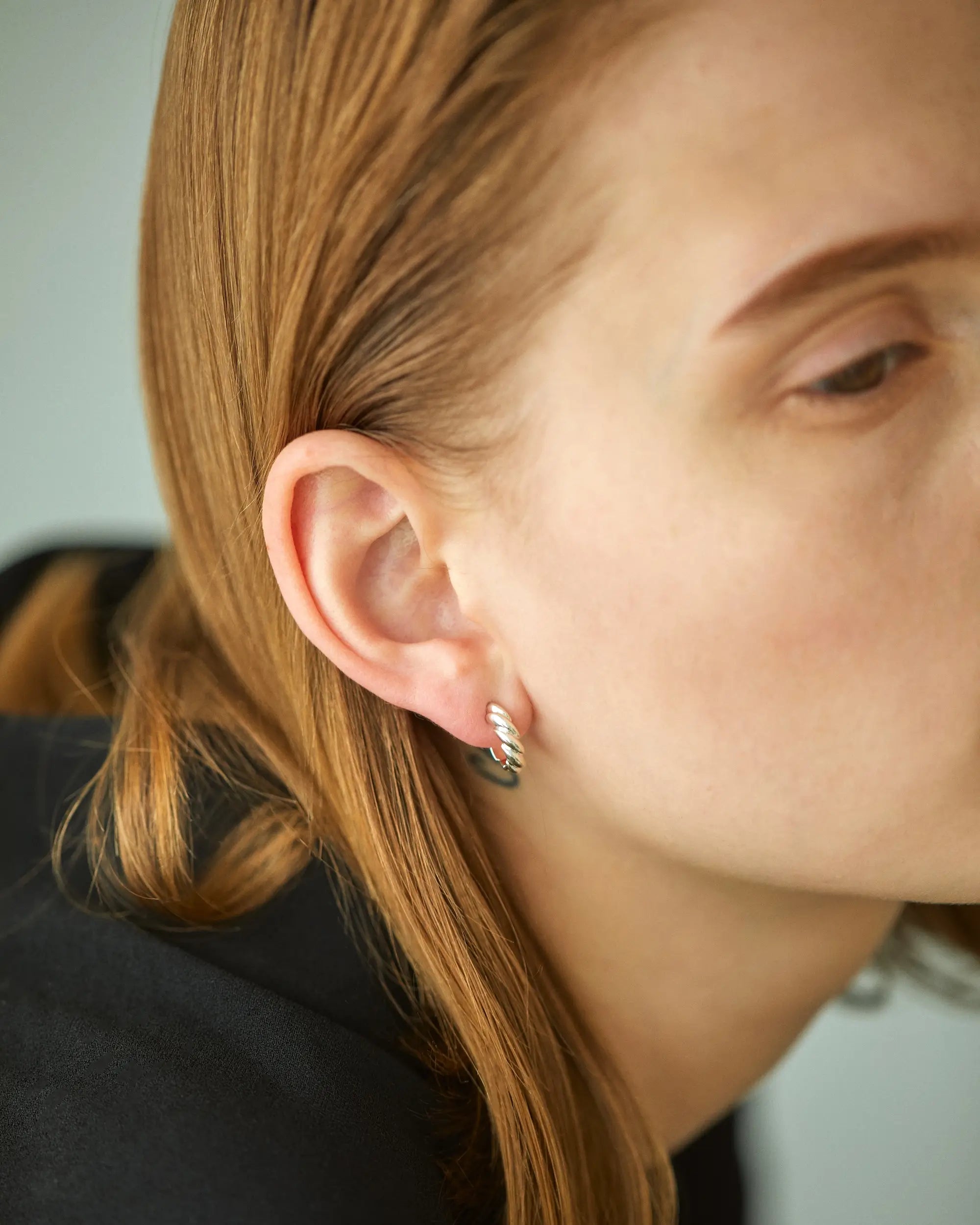 シルバー925素材のウェーブピアス(Sサイズ)を右耳に着用した女性のクローズアップ。肌に馴染む小ぶりなサイズ感がわかります。