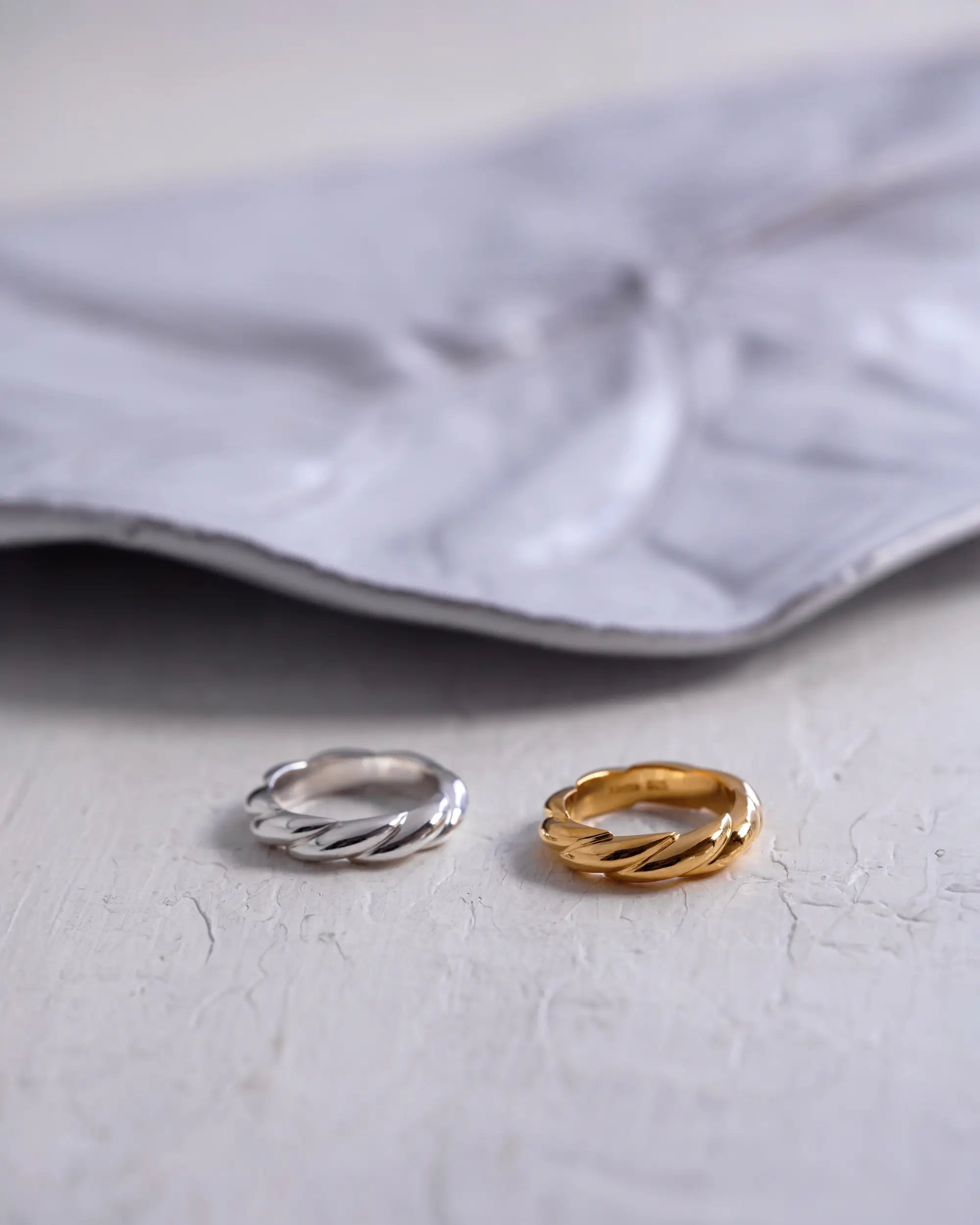 ウェーブリング(シルバー・ゴールド)の商品置き画アップ。指にやさしく寄り添うシームレスな造形で重ね付けにも最適。