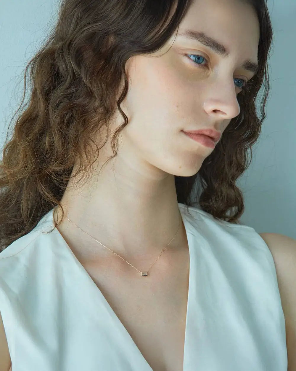 白のVネックトップスに合わせたK10ホワイトトパーズネックレスの洗練された着用コーディネート