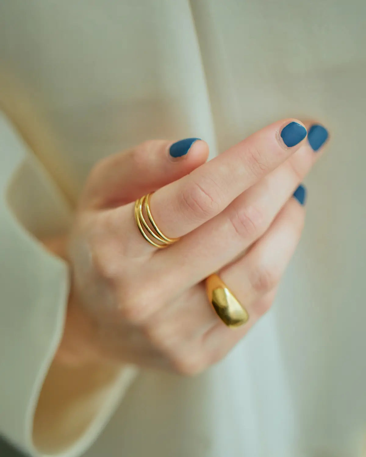 ゴールドのウェーブリングとボリュームのあるリングを組み合わせた、おしゃれな重ね付けコーディネート。
