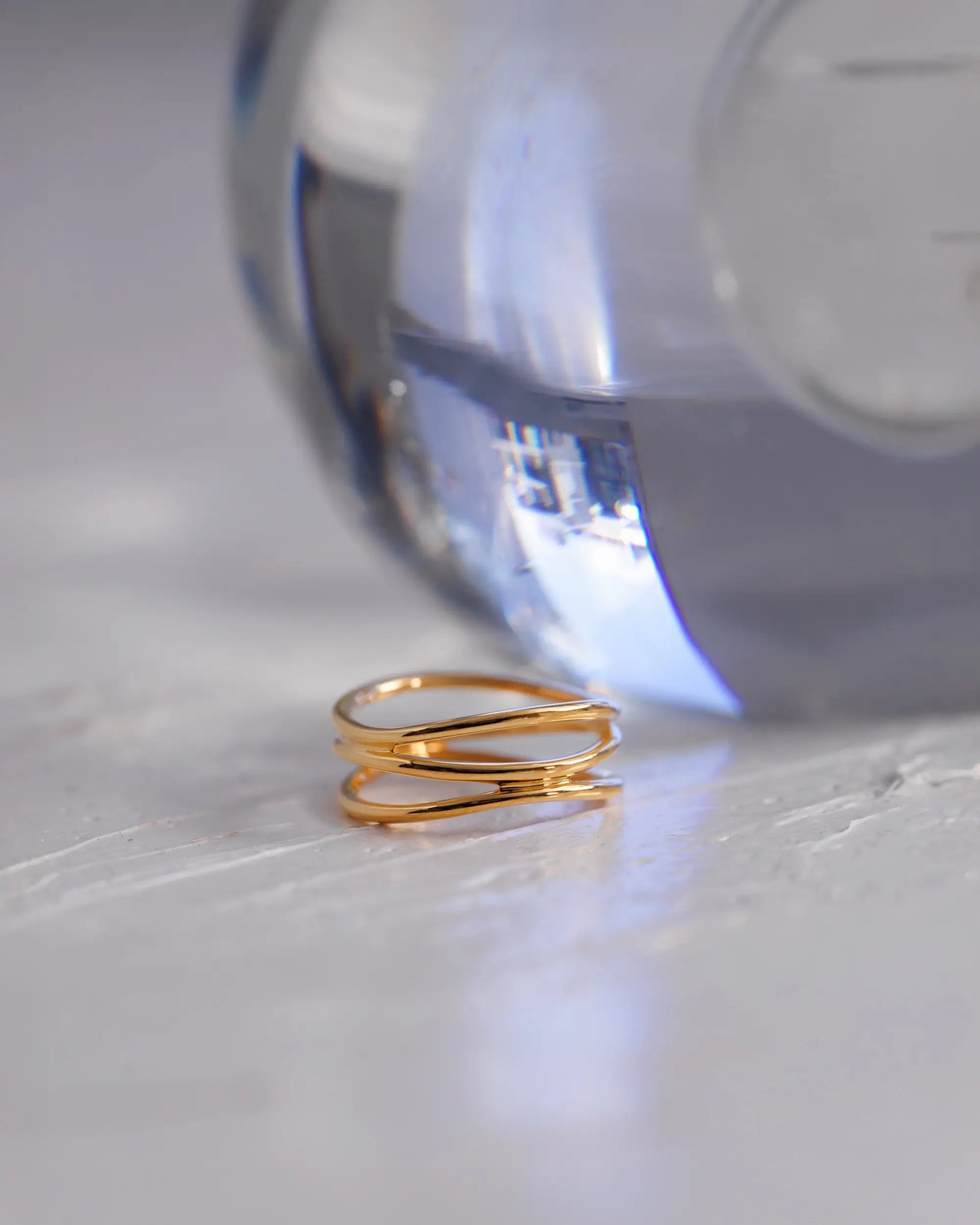 透明なガラス瓶にあしらったゴールドの3ロウウェーブリング。タイムレスで洗練されたデザインのイメージカット。