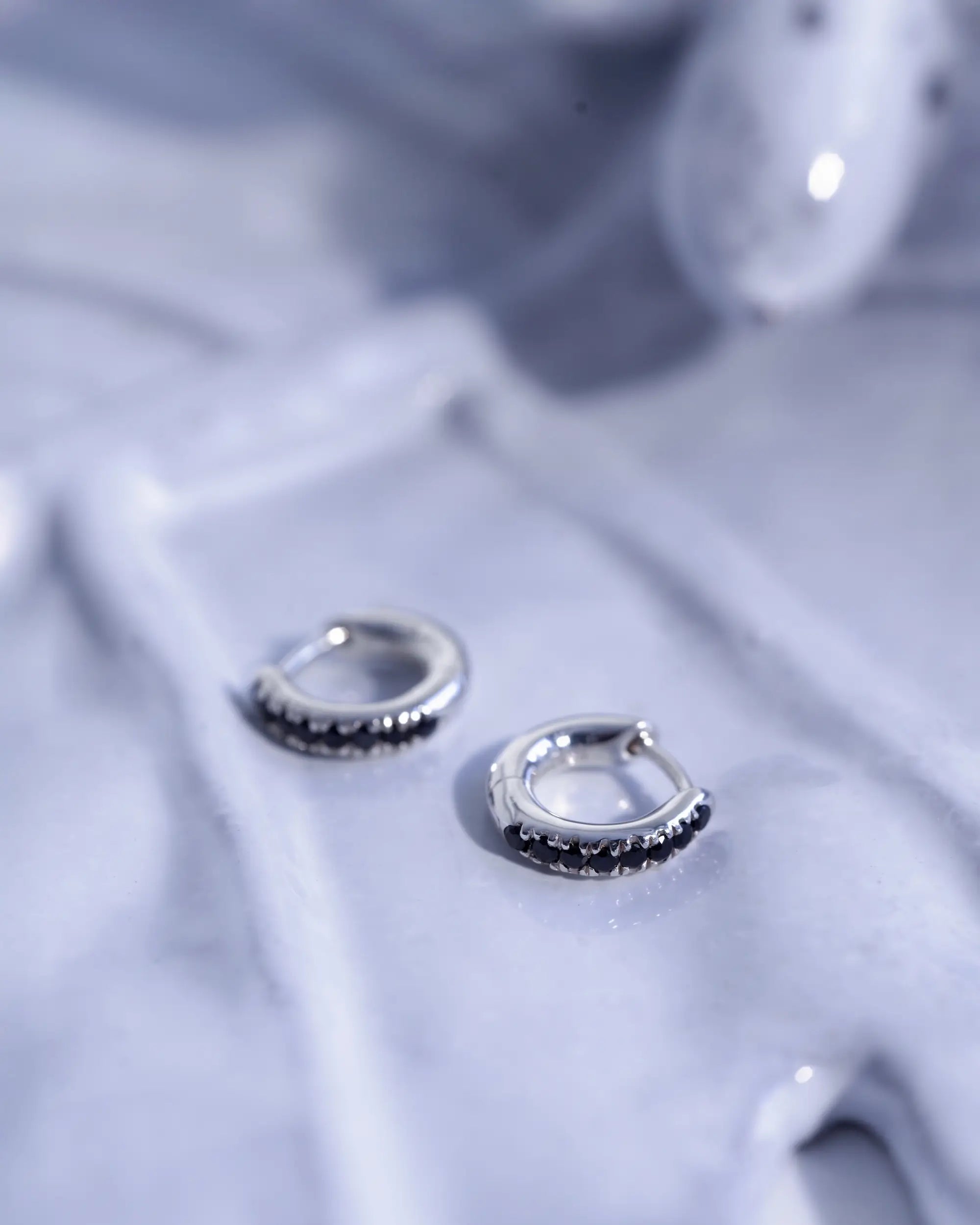 中折れ式で小さいサイズのアビスフープピアス。黒いオニキスが並ぶシンプルなデザインで、ユニセックスなペアジュエリーとしても人気。