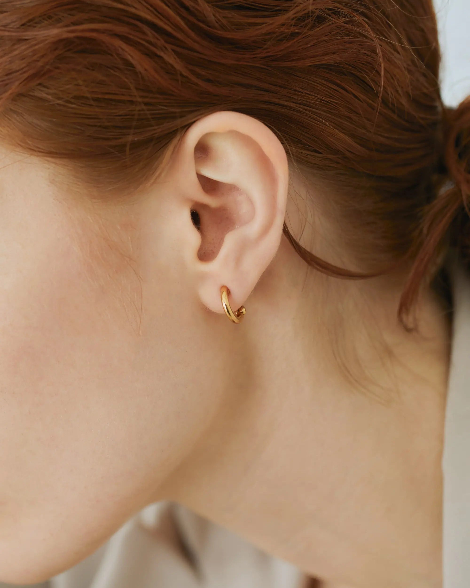 落ちにくいホールド感とストレスフリーを両立したクラシックフープイヤリング（ゴールド）の着用アップ画像。