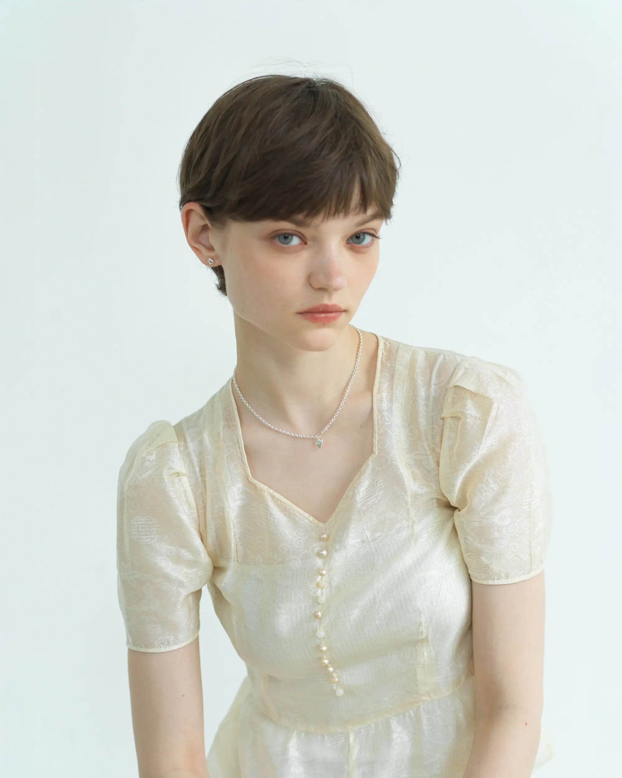 ハートラティスネックレスの着用イメージ。首元に馴染む小ぶりなシルバーのハートが、日常の装いに上品なアクセントをプラス。