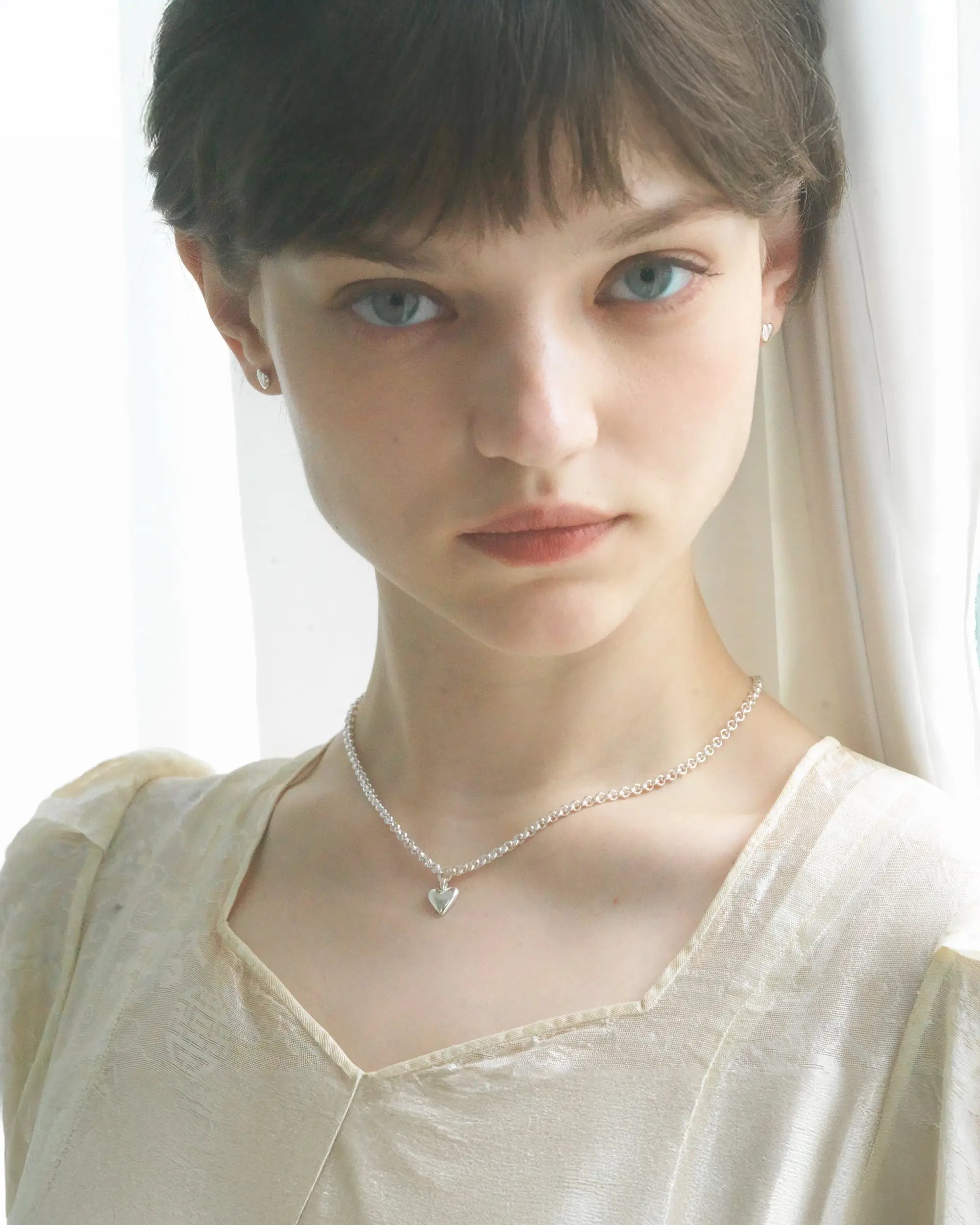 女性の首元を美しく見せるハートモチーフのシルバーネックレス。ロマンティックなデザインは、大切な人へのプレゼントやギフトにも最適。