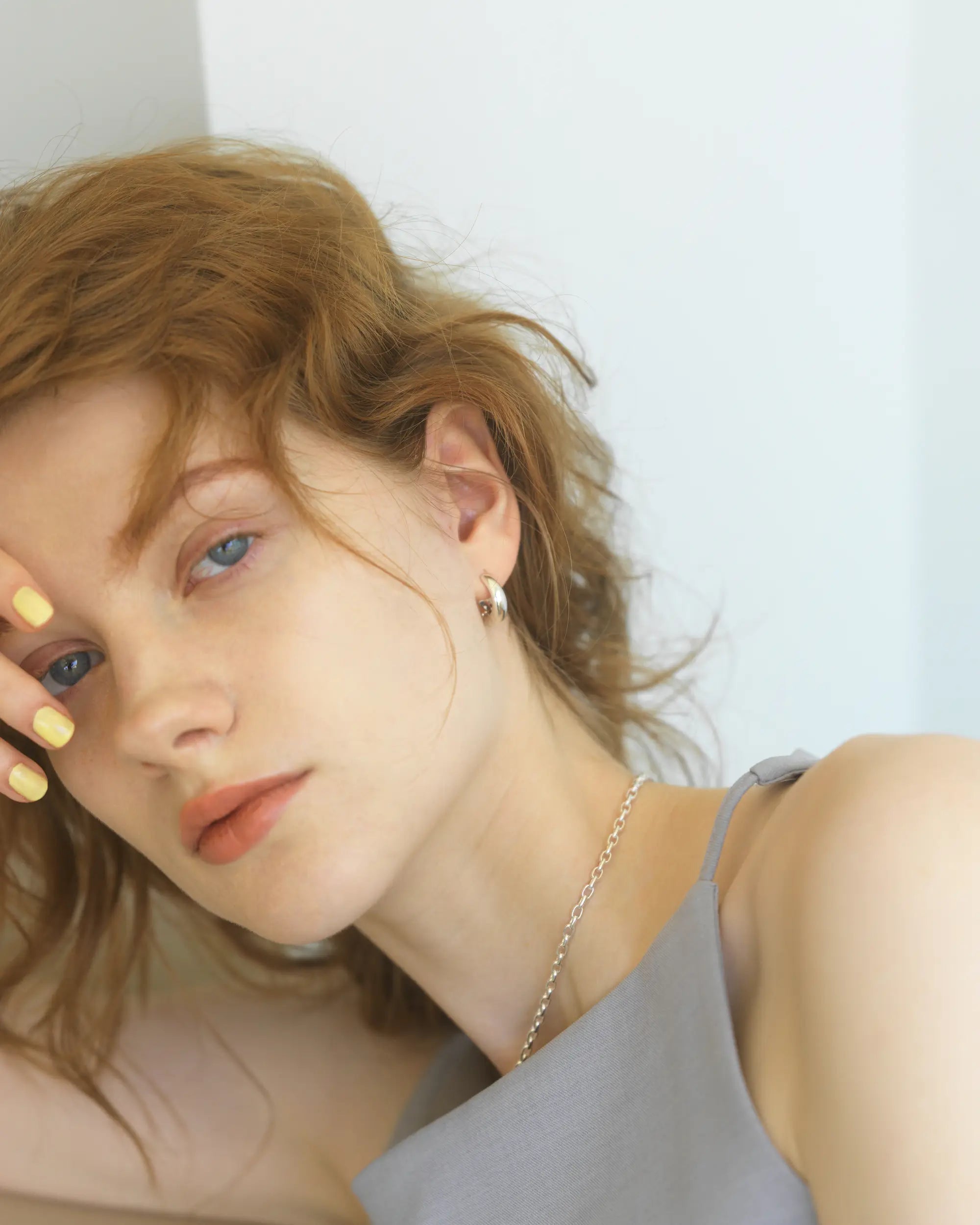 チャンキーな存在感を放つ、大ぶりなバネ式シルバーイヤリングを着用し、カメラを見つめる女性モデルのエフォートレスな姿。