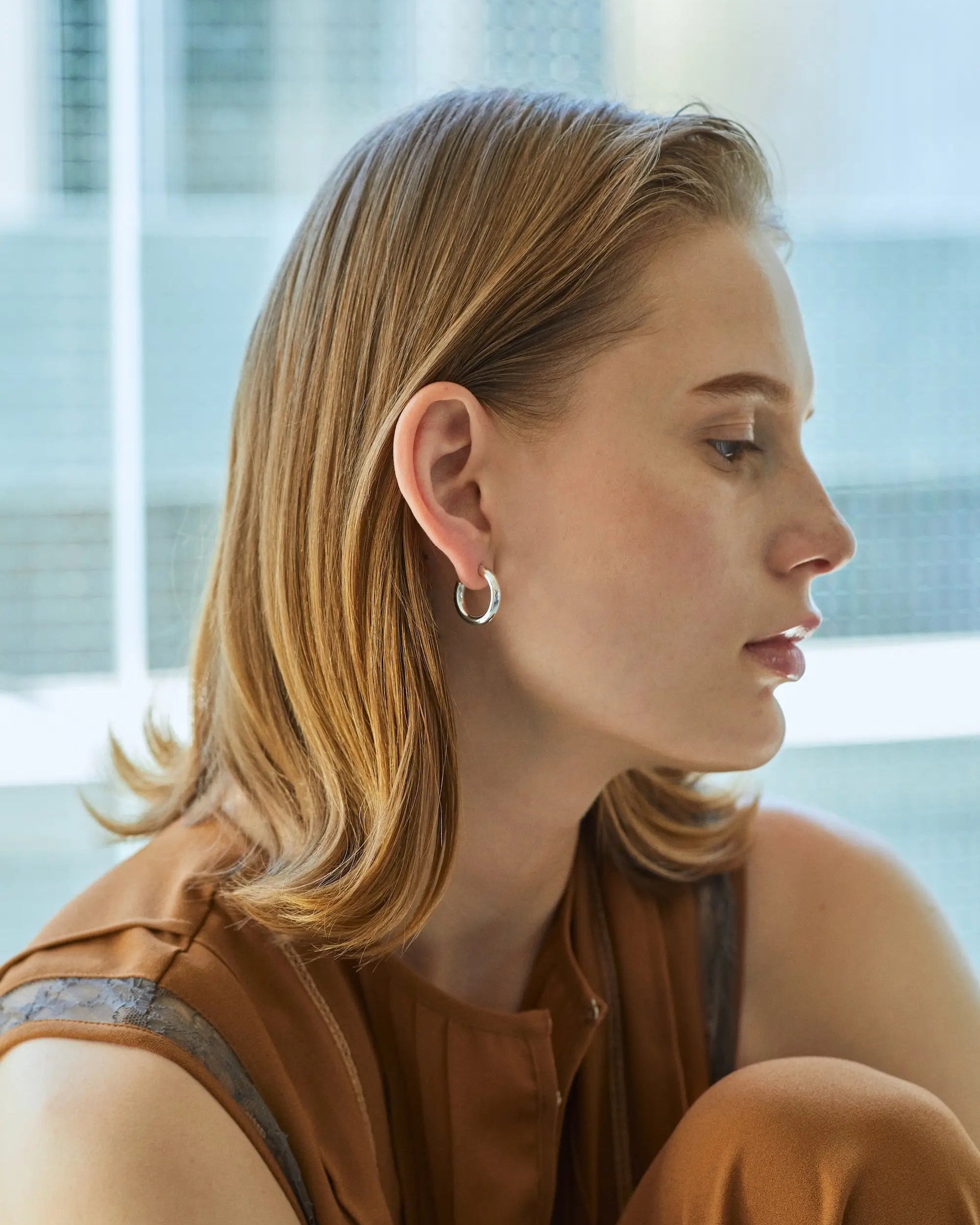 シルバー925製オーバルフープピアス Mを着用した女性モデル。丸いフープにはないスマートな印象を与える、つけっぱなし対応のニッケルフリーピアス。