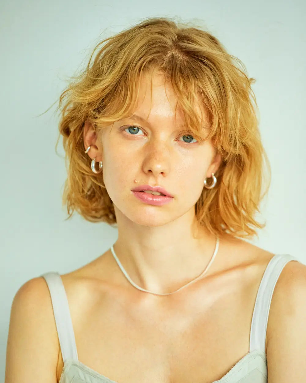 プランプフープピアス（シルバー）を着用した女性モデル。直径約20mmの程よいサイズ感が顔周りを華やかに彩る大ぶりピアス。